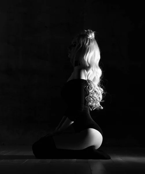 Νέοι σέξι ξανθιά μόδας γυναίκα κάθεται στο ύφασμα μαύρο σώμα και σφικτό επάνω ελαφρύς υπόβαθρο σκοτεινή νύχτα — Φωτογραφία Αρχείου