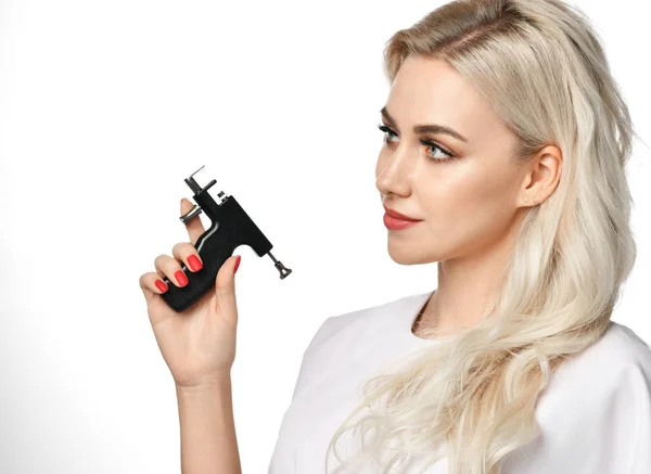 Mujer esteticista cosmetólogo mantenga Piercing de oído pistola mirando a la esquina aislado en blanco — Foto de Stock