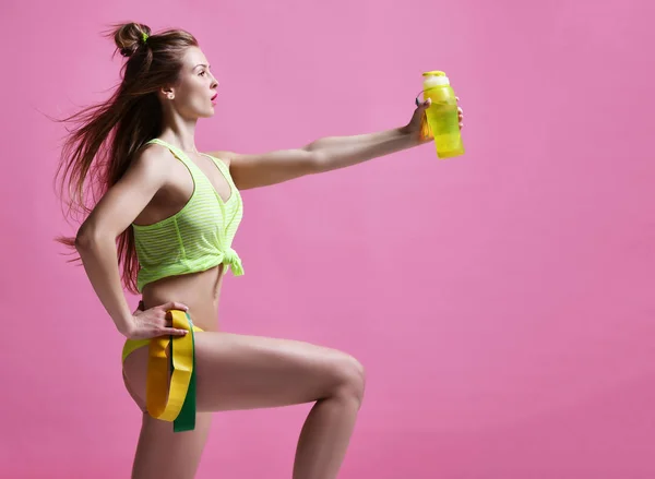 Giovane donna sportiva con bottiglia di acqua potabile e elastico verde e giallo — Foto Stock