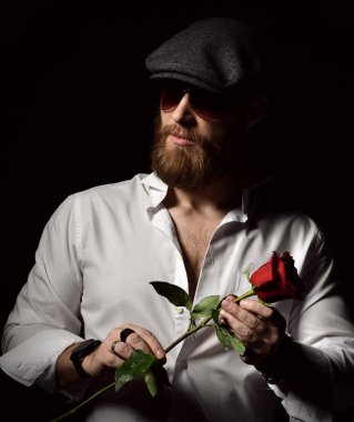 Acımasız adam sakallı ve tarih için kırmızı gül tutan şapka ile 