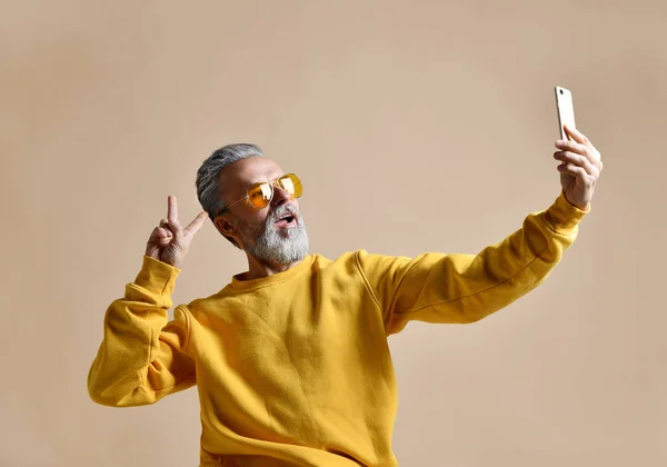 Retrato de hombre millonario feliz senior usando teléfono celular inteligente hacer selfie en gafas de sol amarillas —  Fotos de Stock
