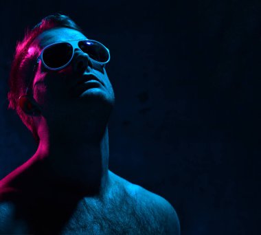 Seksi acımasız adam kas vücut ararken koyu arka plan üzerinde beyaz güneş gözlüğü Neon ışık portresi