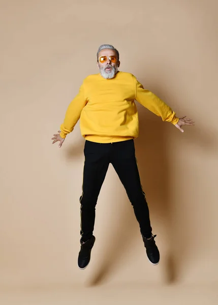 Excited senior millionaire man dancing jumping in yellow sunglasses hands up fashionable men senior — Stock Photo, Image