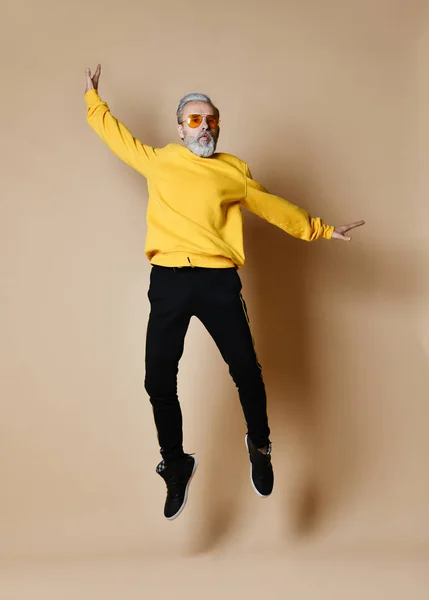 Upphetsad äldre miljonär man dansar hoppning i gula solglasögon händer upp moderiktiga män senior — Stockfoto