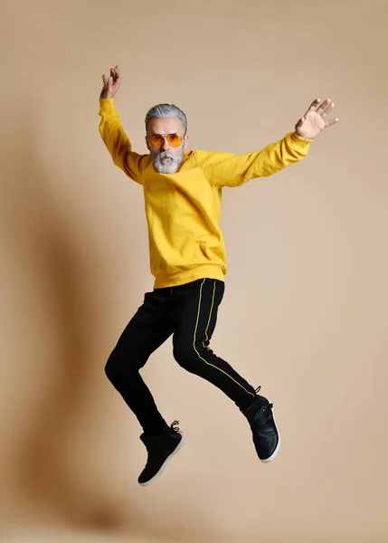 Upphetsad äldre miljonär man dansar hoppning i gula solglasögon händer upp moderiktiga män senior — Stockfoto