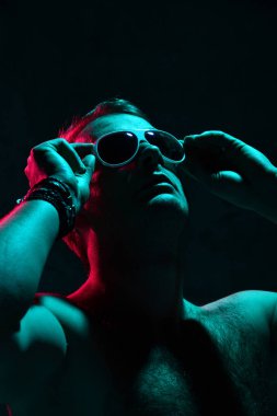 Seksi acımasız adam kas vücut bakmak beyaz güneş gözlüğü Neon ışık portresi