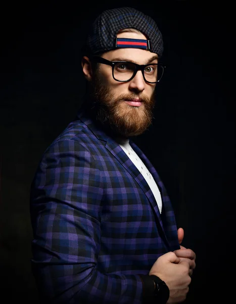 Brutal business man with beard mustache and glasses in fashion cap and blue square jacket — Stock Photo, Image