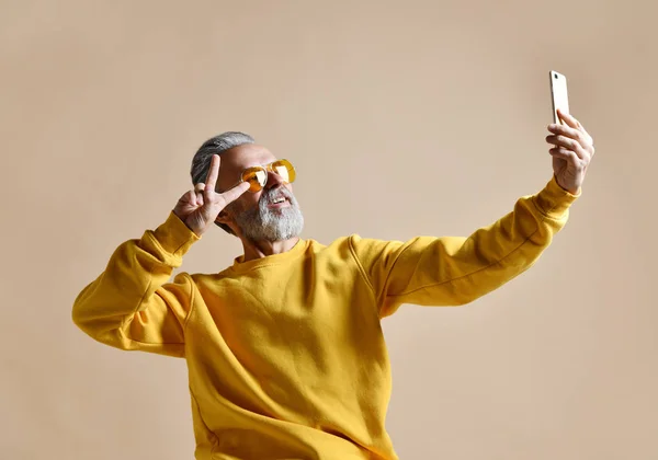 Retrato de feliz homem milionário sênior usando smartphone celular fazer selfie em óculos de sol amarelos — Fotografia de Stock