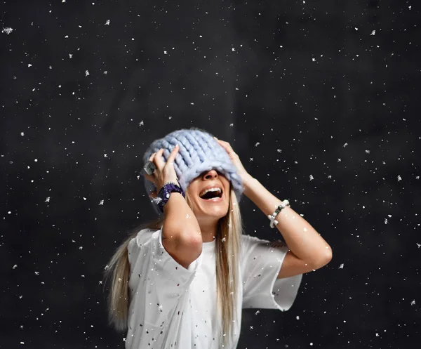 Blonde vrouw in lichte blauwe gebreide muts gelukkig lachend vergadering onder sneeuwvlokken wintertijd — Stockfoto