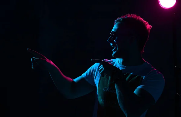 Neon luz retrato de sexy homem muscular corpo e branco t-shirt apontando mãos dedo no canto — Fotografia de Stock