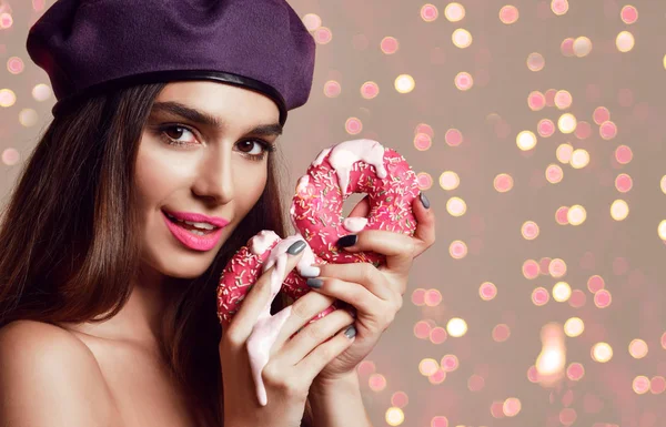 Vrouw houd zoete roze suiker donuts hongerige mond op lichte bruine achtergrond — Stockfoto