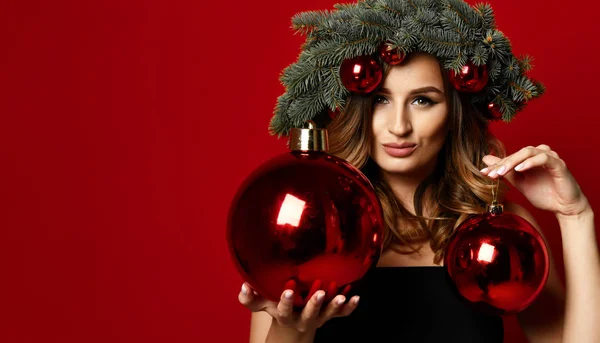 Vacker kvinna med jul spruce fir krans med kottar och nyår dekoration bollar på rött — Stockfoto