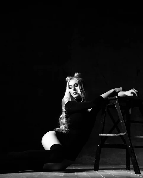 Mladá sexy blondýnka módní ženu sedící na podlaze v černé tělo šaty na pozadí temné noci — Stock fotografie
