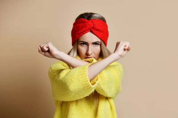 Жінка показує знак NO з хрестиком зупинити жест в жовтому светрі і червоній смузі голови з впевненим обличчям — стокове фото