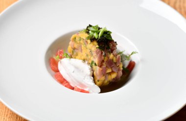 Deniz ürünleri ton balıklı tartar salata beyaz tabakta ekşi krema ile