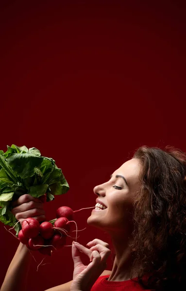 Mujer sostiene rábano fresco con hojas verdes.Dieting. Concepto de alimentación saludable sobre fondo rojo para historia de instagram —  Fotos de Stock