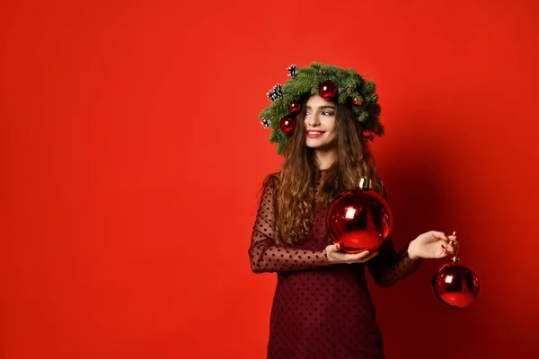 Mulher bonita com Natal abeto grinalda de abeto com cones e bolas de decoração do ano novo no vermelho — Fotografia de Stock