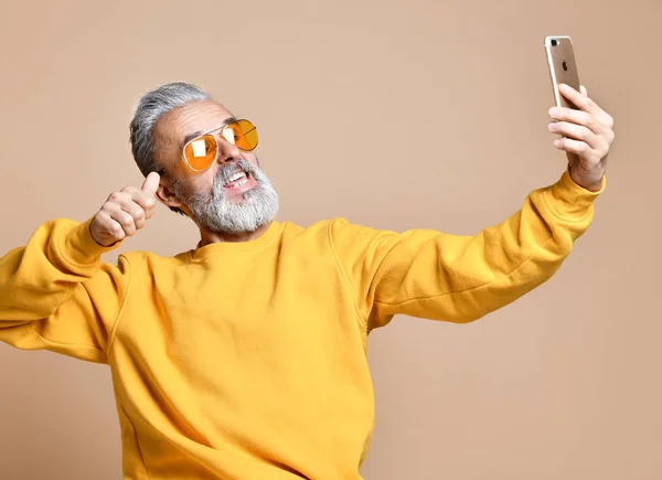 Retrato de hombre millonario feliz senior usando teléfono celular inteligente hacer selfie en gafas de sol amarillas —  Fotos de Stock