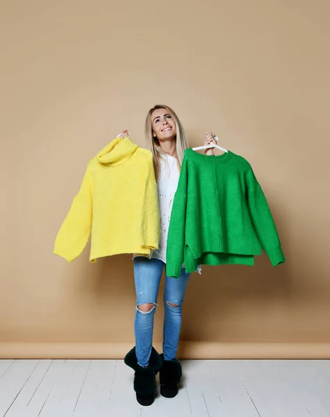 Mujer de compras venta de Navidad elegir entre dos suéteres blusa verde y amarillo feliz sonrisa — Foto de Stock