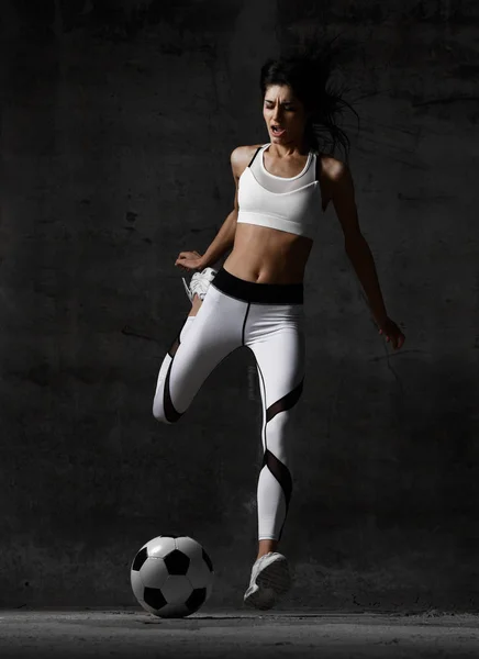 Femme joueur courir sauter et frapper ballon de football hurlant sur sombre — Photo