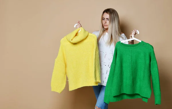 Рождественская распродажа женщины выбрать между двумя свитерами блузка зеленый и желтый счастливый улыбаясь — стоковое фото
