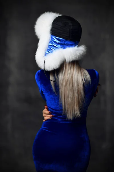 苗条的年轻女子在新的蓝色时装和北极狐狸冬季毛皮耳朵皮瓣帽子从后面的看法 — 图库照片
