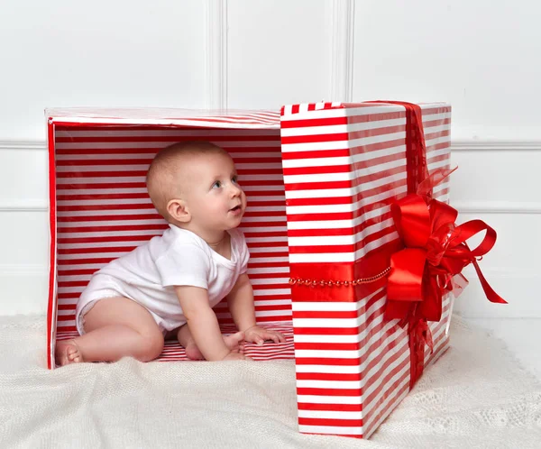Dítě dítě batole dítě sedí v big red představuje etui na oslavu Vánoce — Stock fotografie