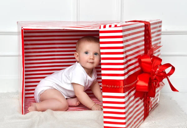 Kind kind baby peuter jongen zitten in grote rode presenteert gift box voor viering kerst — Stockfoto