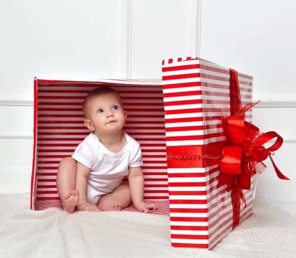 Niño bebé niño pequeño sentado en grandes regalos rojos caja de regalo para la celebración de Navidad — Foto de Stock