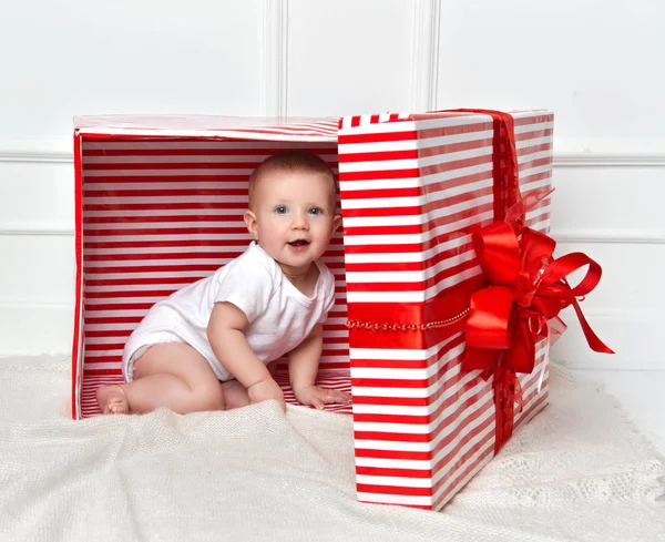 Kind kind baby peuter jongen zitten in grote rode presenteert gift box voor viering kerst — Stockfoto