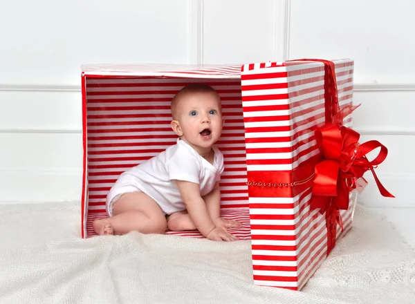 Kind kind baby peuter jongen zitten in grote rode presenteert gift box voor viering kerst — Stockfoto