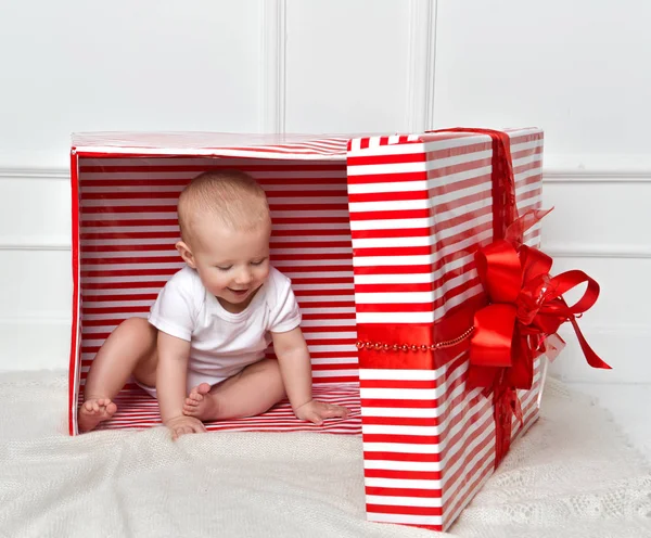 Niño bebé niño pequeño sentado en grandes regalos rojos caja de regalo para la celebración de Navidad — Foto de Stock