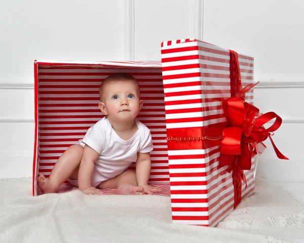 Kind kind baby peuter jongen zitten in grote rode presenteert gift box voor viering kerst — Stockfoto