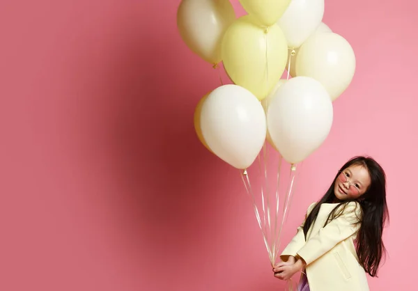 Kleines asiatisches Mädchen in gelber Modejacke und lila Kleid mit Luftballons feiert fröhliches Lächeln — Stockfoto