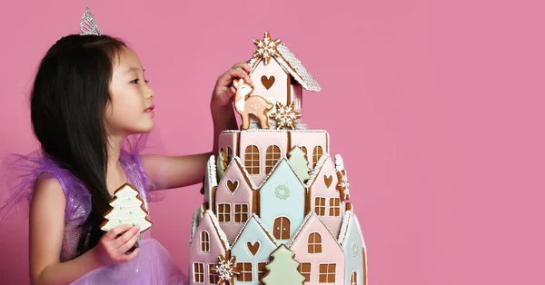 Piccola ragazza asiatica in corona e vestito viola con torta di biscotti allo zenzero per la festa di compleanno — Foto Stock