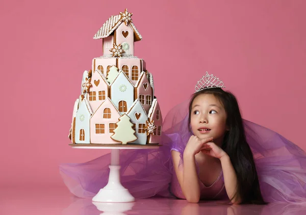 Piccola ragazza asiatica in corona e vestito viola con torta di biscotti allo zenzero per la festa di compleanno — Foto Stock