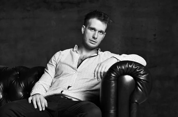 Jovem homem de negócios sentado no sofá cadeira Chester couro na camisa casual pensando — Fotografia de Stock