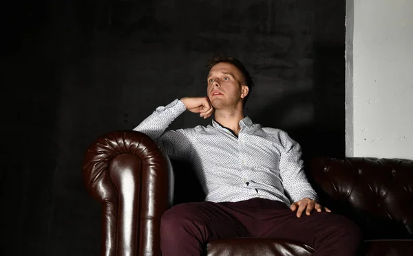 カジュアル シャツ思考の革チェスターのアームチェア ソファに座っている若いビジネスマン — ストック写真