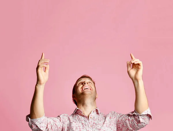 Pembe üzerinde parmak eller yukarıyı tişörtlü mutlu genç gülümseyen adam — Stok fotoğraf