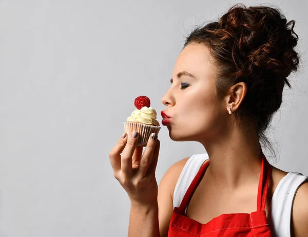 Młoda kobieta kucharz trzymać słodkie ciasto z kremem i truskawkami szczęśliwy, patrząc na rogu — Zdjęcie stockowe
