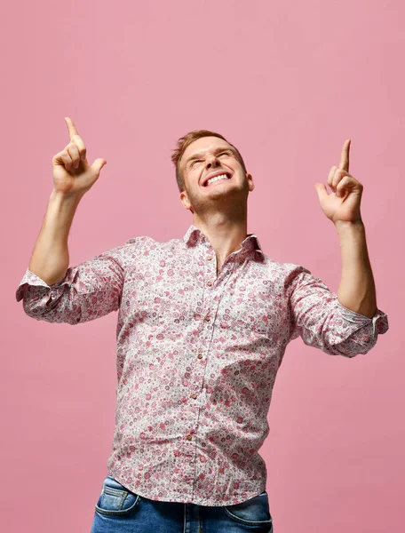 Joven hombre sonriente feliz con la camisa señalando las manos hacia arriba en rosa —  Fotos de Stock