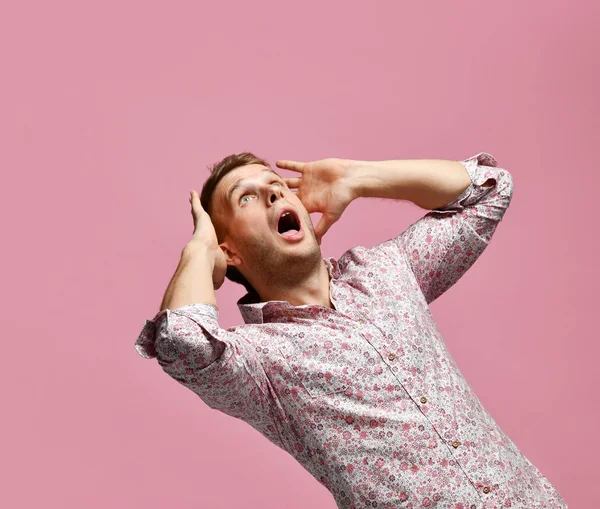 Joven hombre salido asustadizo sorprendido en camisa afortunado ganador gritando mirando hacia arriba en rosa —  Fotos de Stock