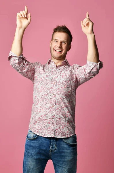 Joven hombre sonriente feliz con la camisa señalando las manos hacia arriba en rosa — Foto de Stock