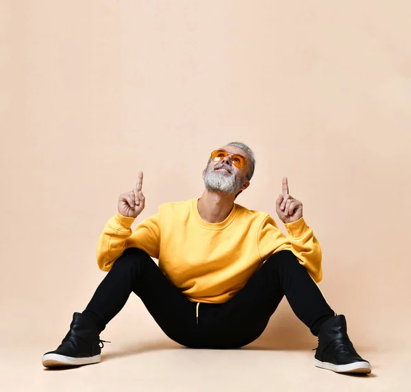 Portrait of gray hair senior millionaire man in yellow sunglasses pointing fingers up — Stock Photo, Image