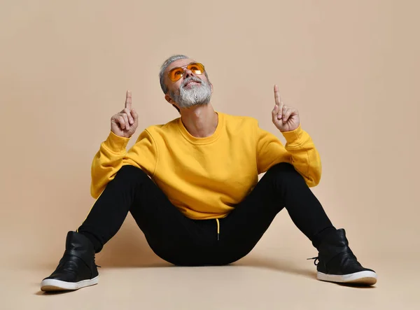 Portrait of gray hair senior millionaire man in yellow sunglasses pointing fingers up — Stock Photo, Image