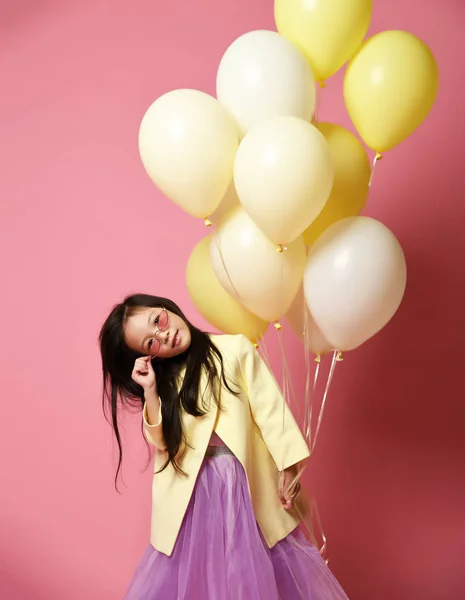 Kleine Koreaanse babymeisje in het geel mode jas en paarse jurk met ballonnen vieren gelukkig lachend — Stockfoto