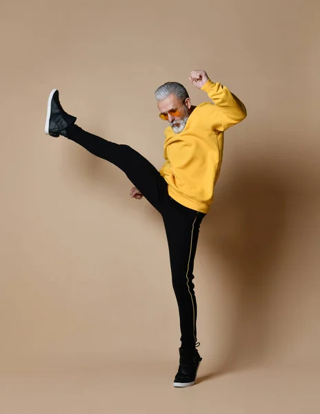 Senior miljonär mannen i gul duk och aviator snygga solglasögon motion stretching hit punch med ben — Stockfoto