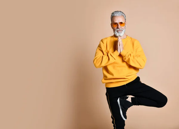 Erkeklerde germe egzersiz yoga asana pratik sarı güneş gözlükleri şık moda mutlu üst düzey milyoner adam portresi — Stok fotoğraf