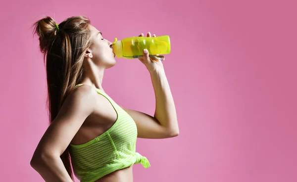 Jonge sport vrouw houd drinkwater sport fles op roze — Stockfoto