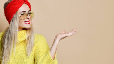 Genç kadın noktası açık el palm için metin alanı ifade duygu moda güneş gözlüğü sarı kazak ve kırmızı dudaklar 